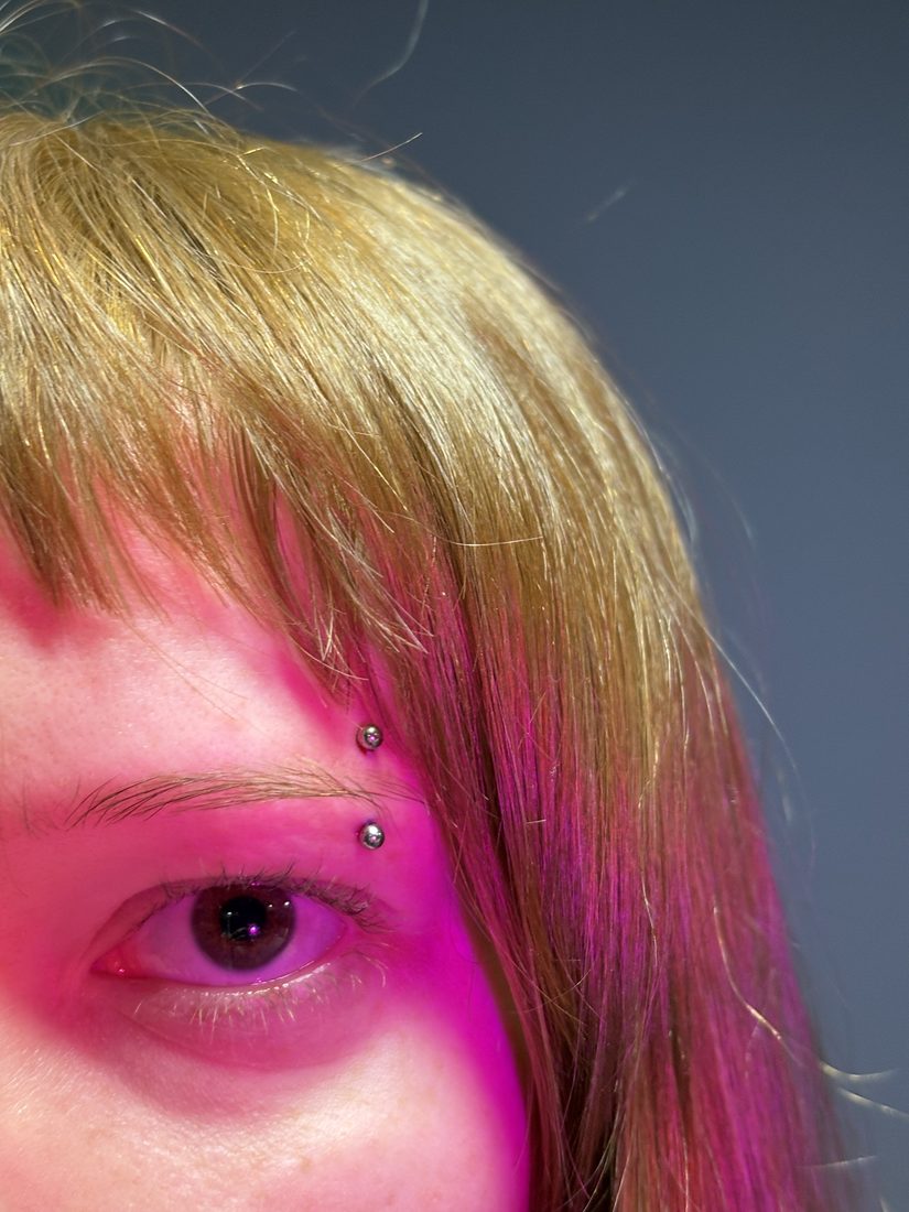 eyebrow piercing, blonde hair, pink light