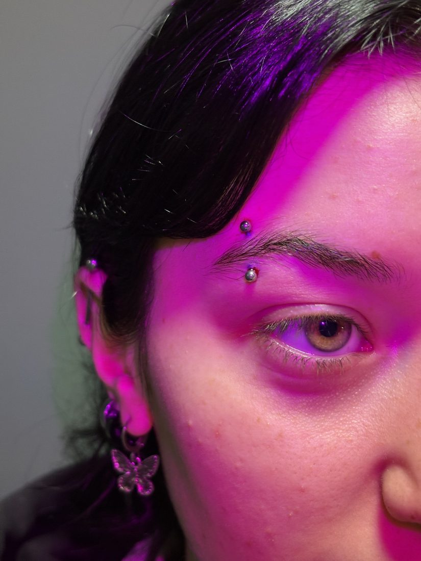 fresh eyebrow piercing under pink light