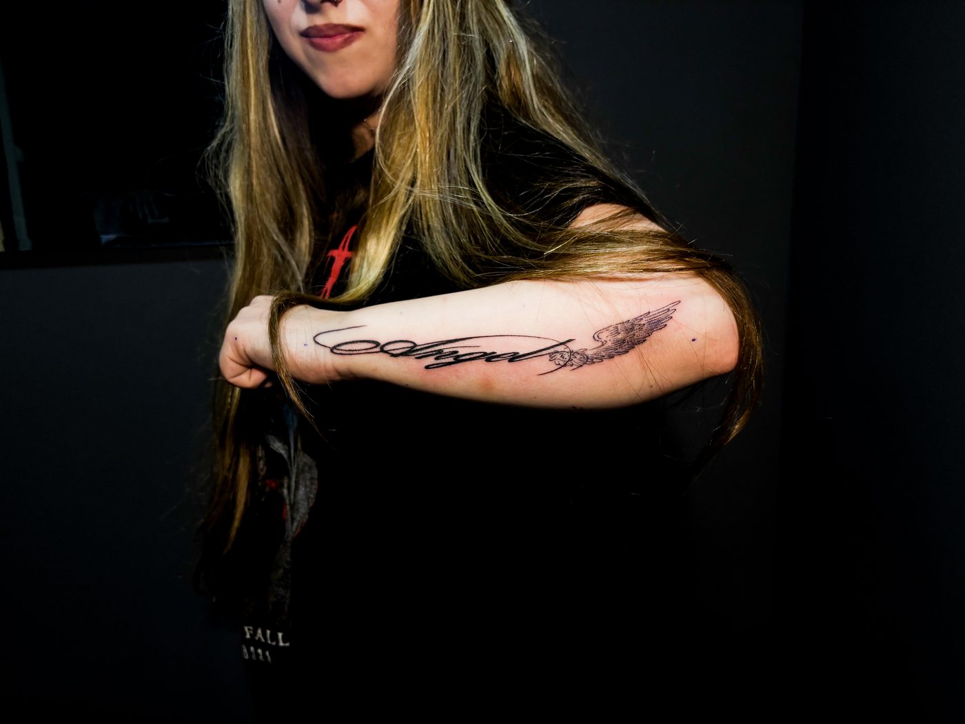angel lettering tattoo on a forearm