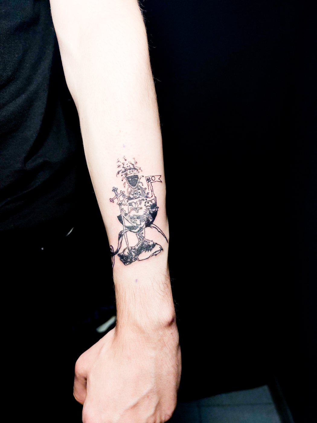 fine line figure tattoo on a forearm, shot on dark fabric