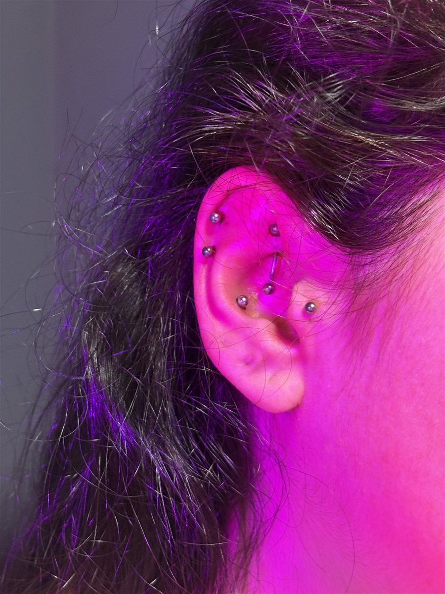 curated ear piercing set glowing under uv pink light