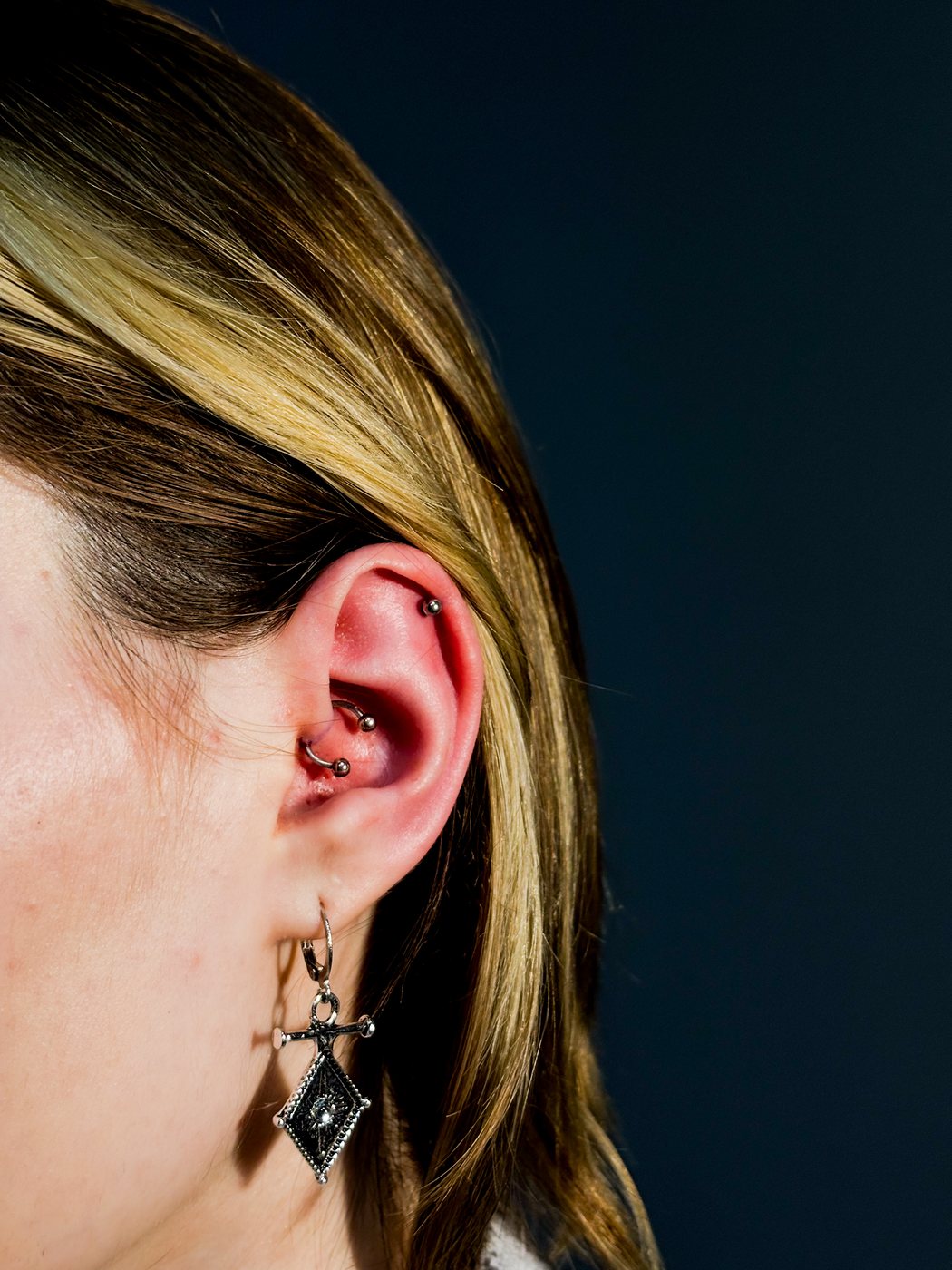 ear styling with dark dangling jewelry on a black background