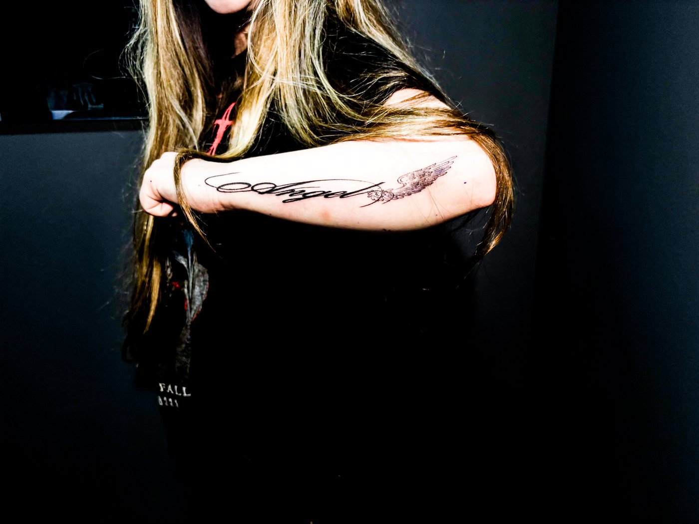custom angel lettering with a wing, fine line on a forearm